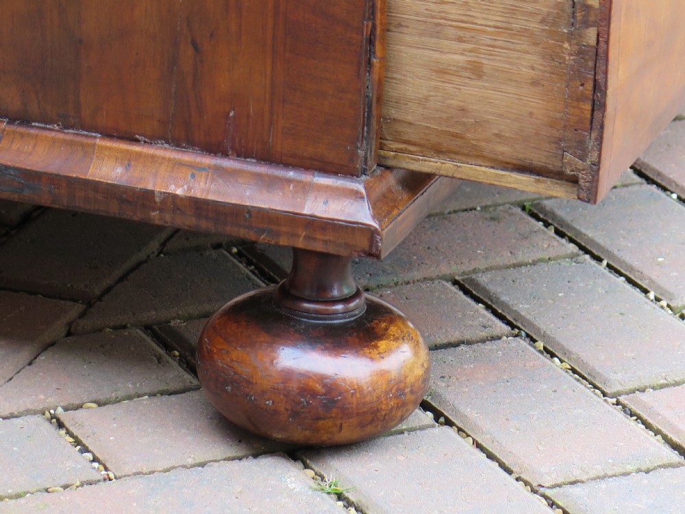 An early 18th-century Queen Anne period walnut chest of drawers featuring two short drawers over three long drawers, standing on turned bun feet. View XV