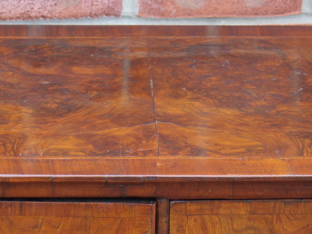 An early 18th-century Queen Anne period walnut chest of drawers featuring two short drawers over three long drawers, standing on turned bun feet. View XXI