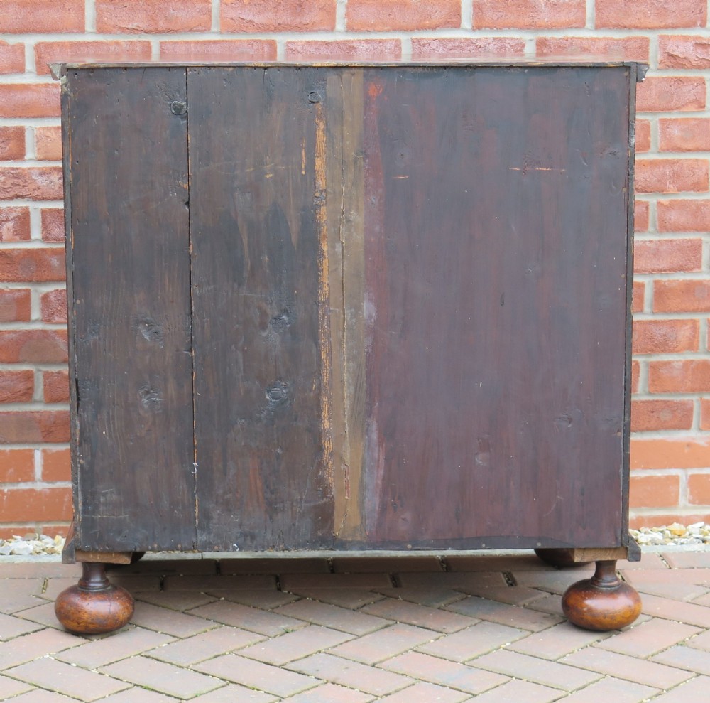 An early 18th-century Queen Anne period walnut chest of drawers featuring two short drawers over three long drawers, standing on turned bun feet. View XXIII