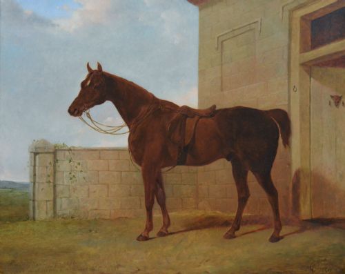 fig 1. An antique oil painting depicting a saddled chestnut hunter horse standing profile against a stone stable wall within a carved gilt wood frame.