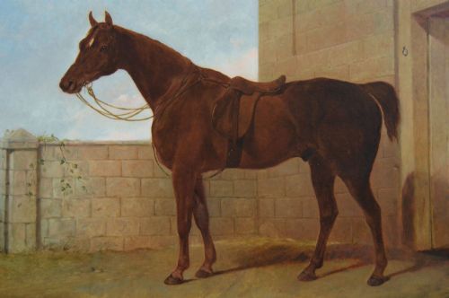 fig 2. An antique oil painting depicting a saddled chestnut hunter horse standing profile against a stone stable wall within a carved gilt wood frame.