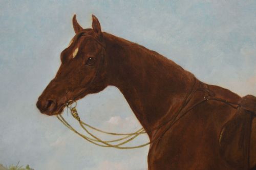 fig 3. An antique oil painting depicting a saddled chestnut hunter horse standing profile against a stone stable wall within a carved gilt wood frame.
