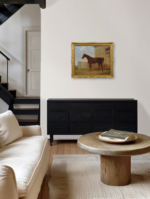 fig 6. An antique oil painting depicting a saddled chestnut hunter horse standing profile against a stone stable wall within a carved gilt wood frame.