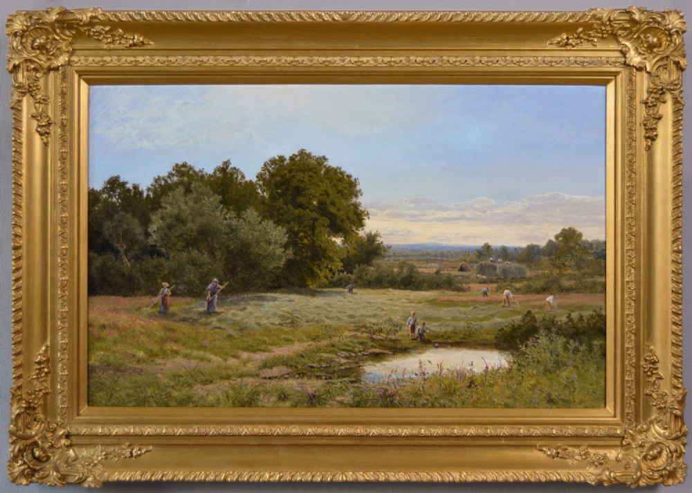 A framed 19th-century oil painting depicting agricultural workers harvesting hay in a green pastoral landscape beside a pond, set within a heavily detailed gold gilded frame.