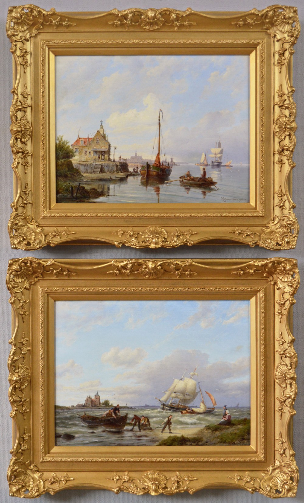 A pair of 19th-century Dutch seascape oil paintings depicting sailing boats along a coastal shore, each enclosed within elaborate gold giltwood frames.
