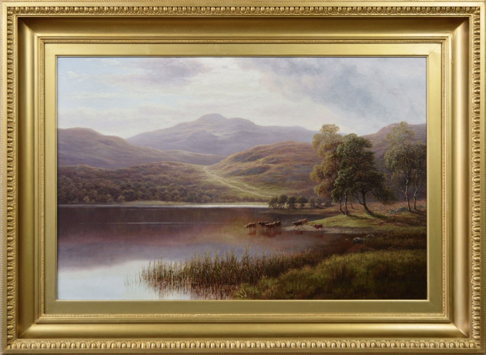 A Victorian landscape oil painting depicting cattle near a reflective lake with surrounding mountains, presented in a gold leaf frame.