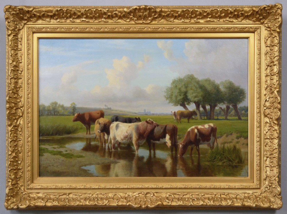 A gilded ornate frame enclosing an oil painting of cattle standing in a stream within a green pastoral landscape.