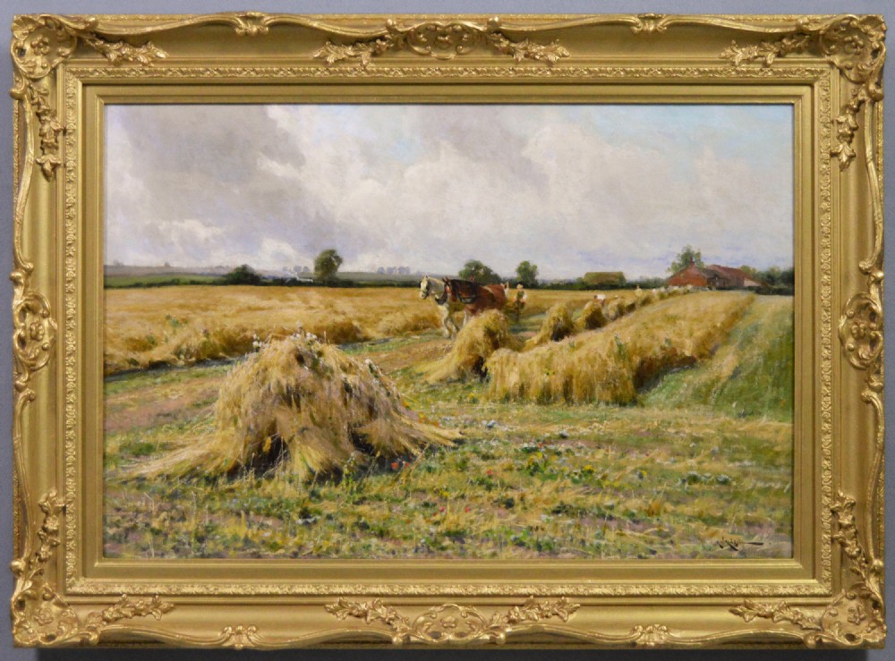 A rural landscape oil painting depicting a wheat harvest with haystacks and horses framed in an ornate gilded frame.