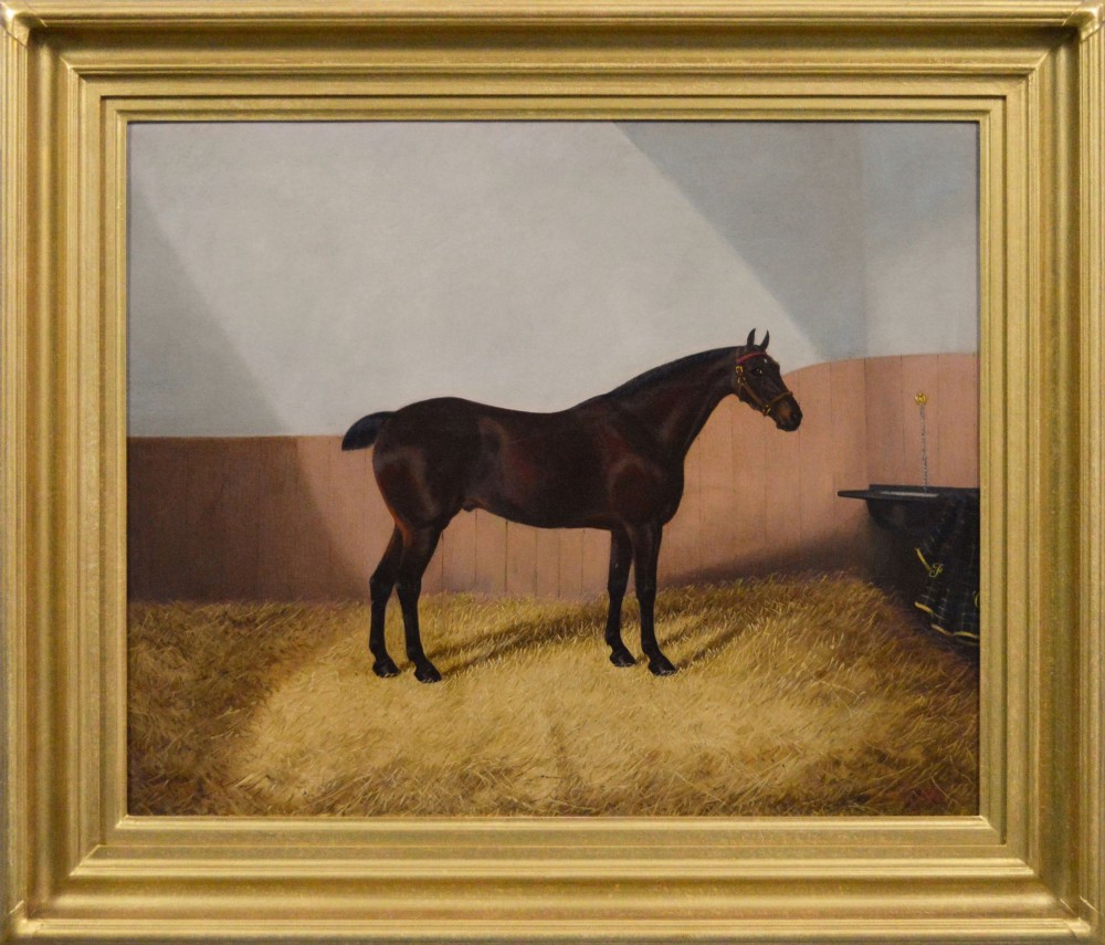 An oil painting depicting a dark bay horse standing in a straw-filled stable stall, encased within a heavy gold gilt frame.