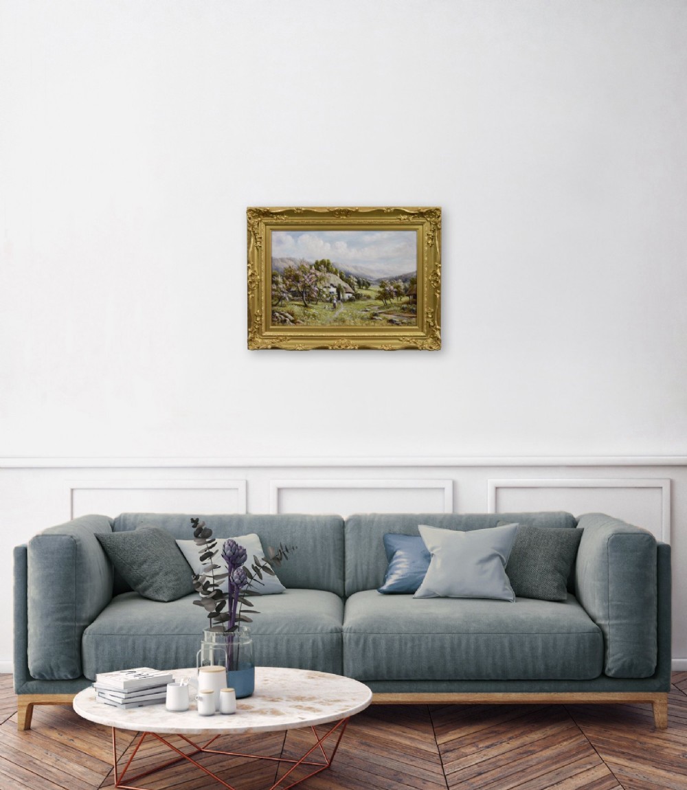 A framed oil painting depicting a thatched rural cottage surrounded by blossom trees with a figure outside and hills in the background. View IX