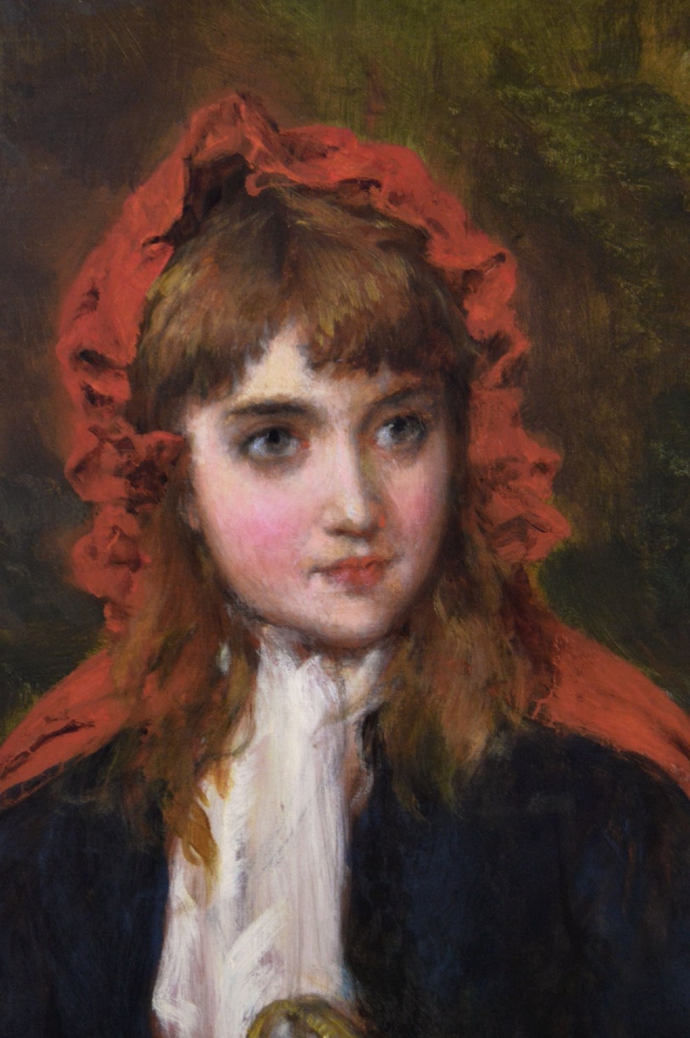 An oil painting depicting a young woman in a red bonnet holding a wicker basket of apples, presented in an ornate gilded frame. View III