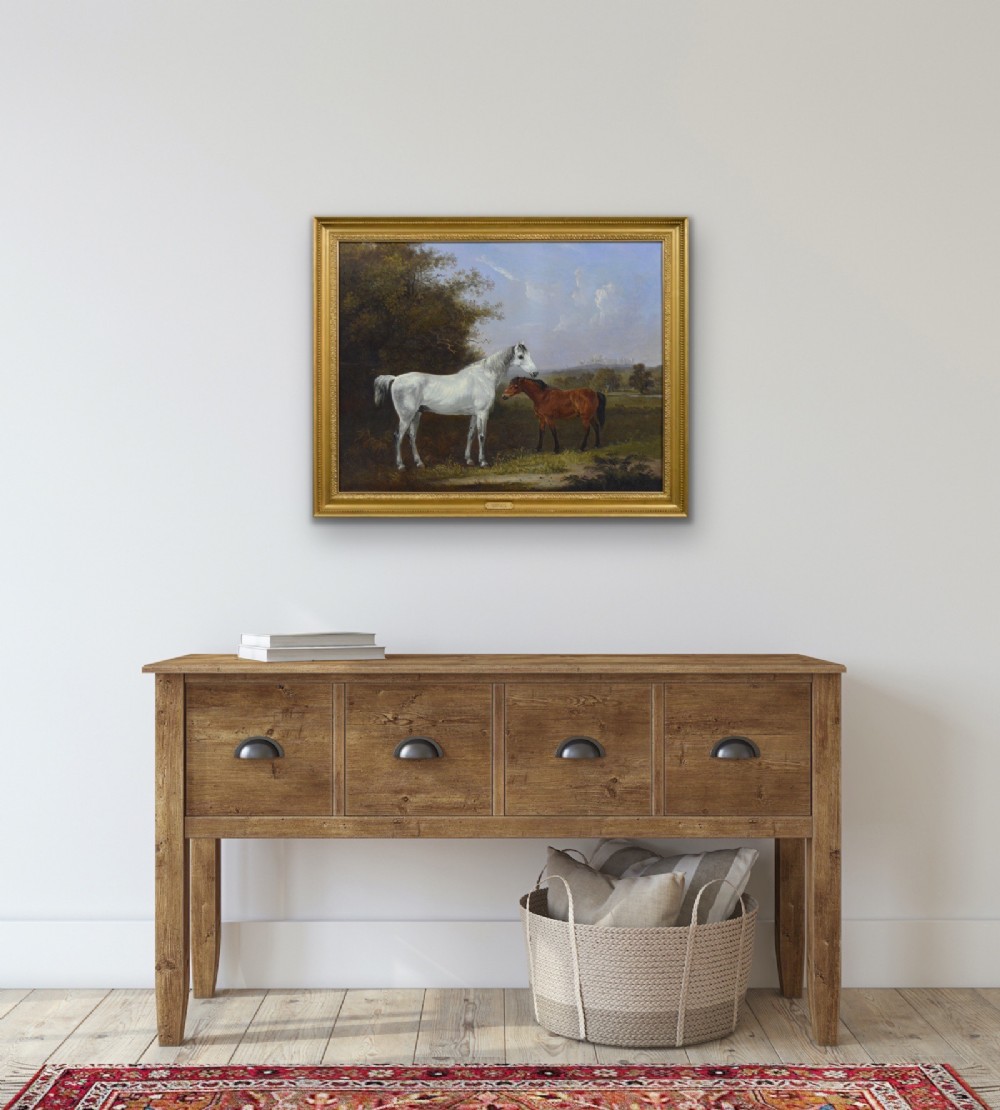 A 19th-century oil painting depicting a grey mare and a bay foal standing in a rural landscape with Windsor Castle in the distance, set within a beaded gold frame. View X