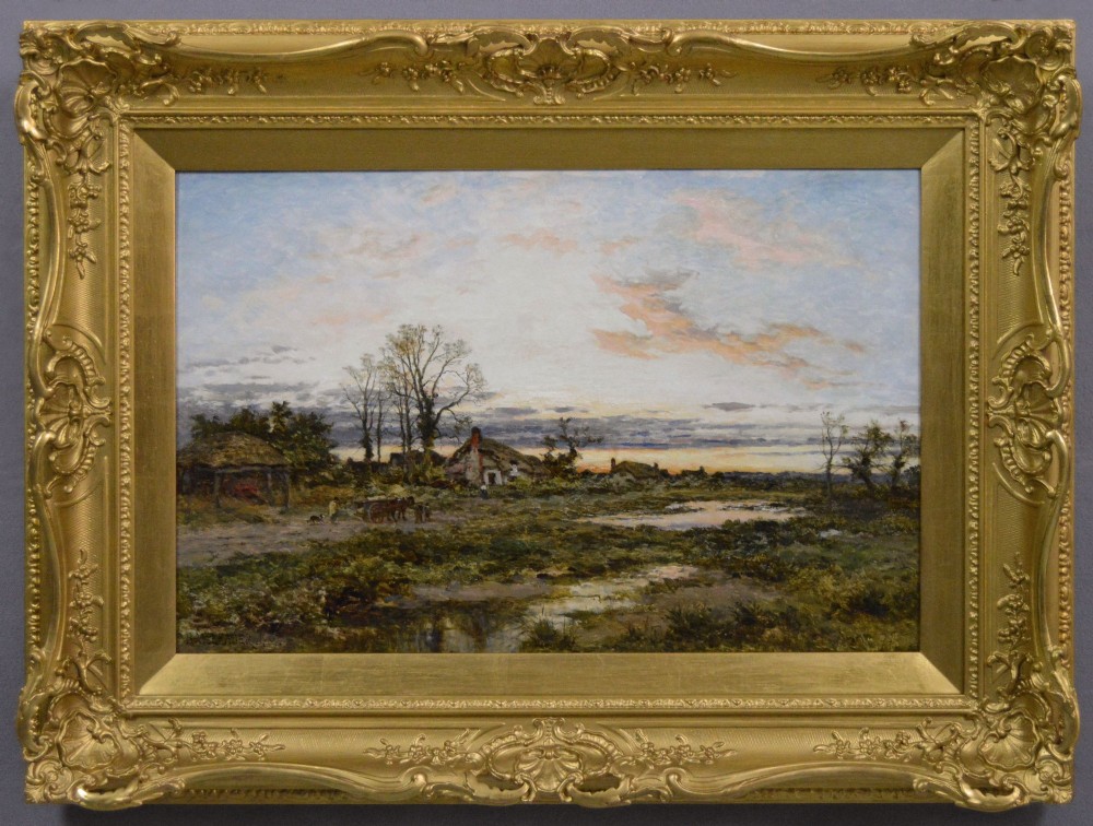 A framed Victorian oil painting depicting a rural English common at dusk with cottages, figures, and water pools set inside an elaborate gold gilt frame.
