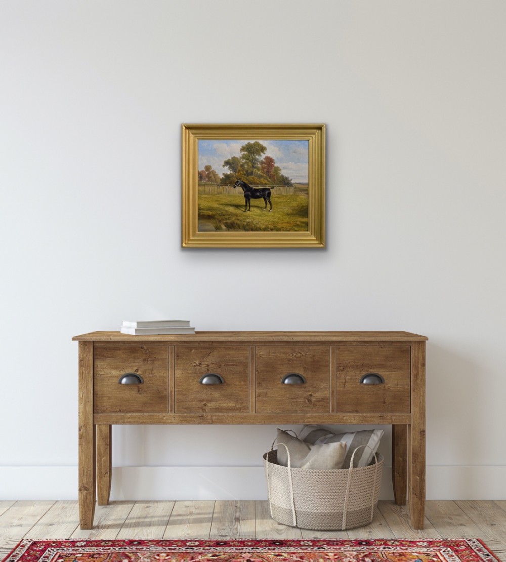 An oil painting depicting a black horse standing in profile within a green pasture, framed in a stepped gold frame. View IX