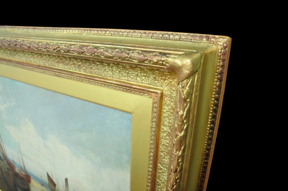A nineteenth-century framed oil painting depicting fishing boats docked at a harbour shore beside coastal buildings, encased in a decorative gold leaf frame. View III