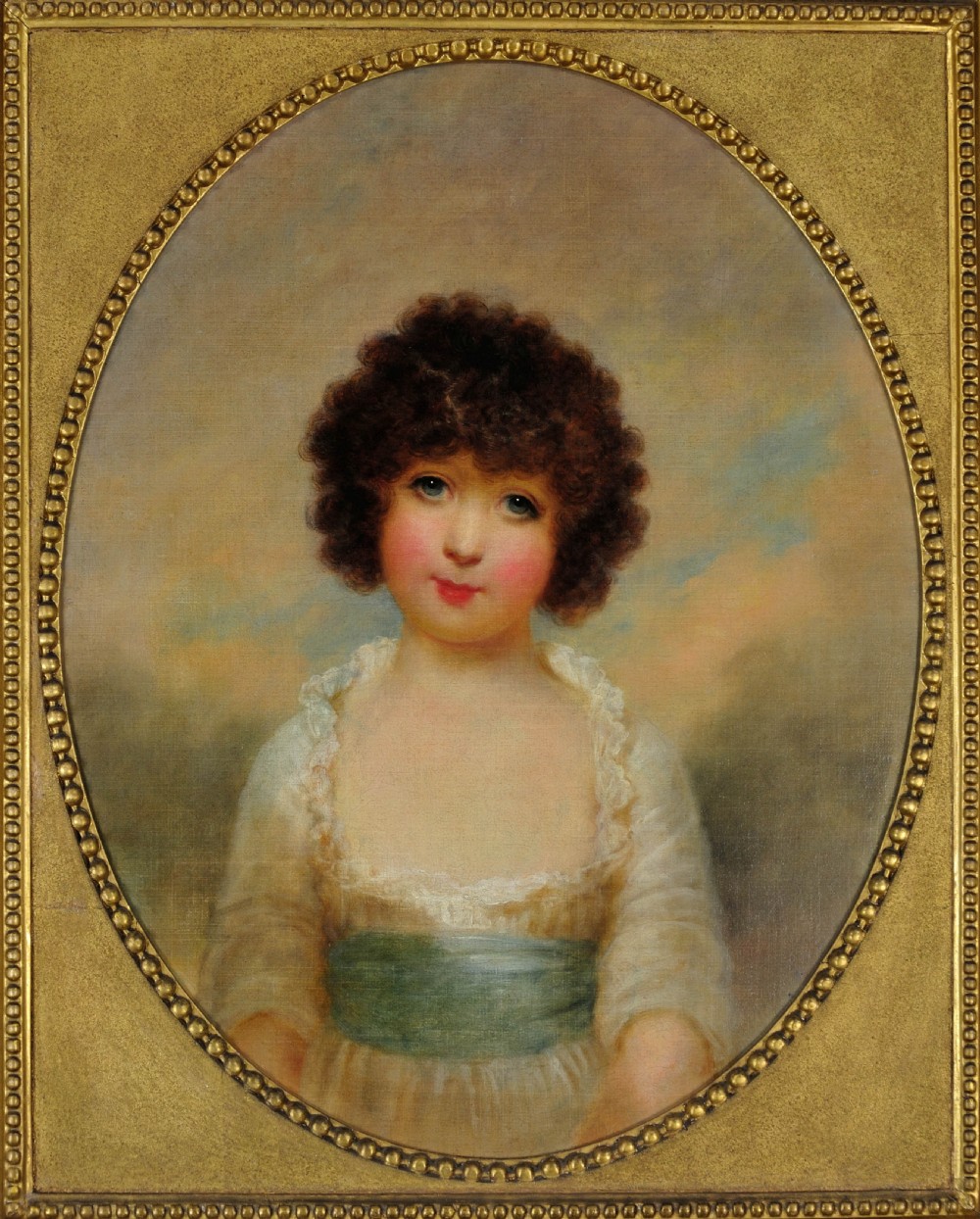An 18th-century oil portrait of a young girl with dark curly hair and a blue sash, presented within an ornate rectangular gilt frame featuring an oval aperture. View II