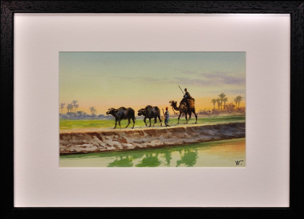 A framed watercolour painting depicting Egyptian farmers leading livestock and a rider on a camel along a canal bank at sunset.