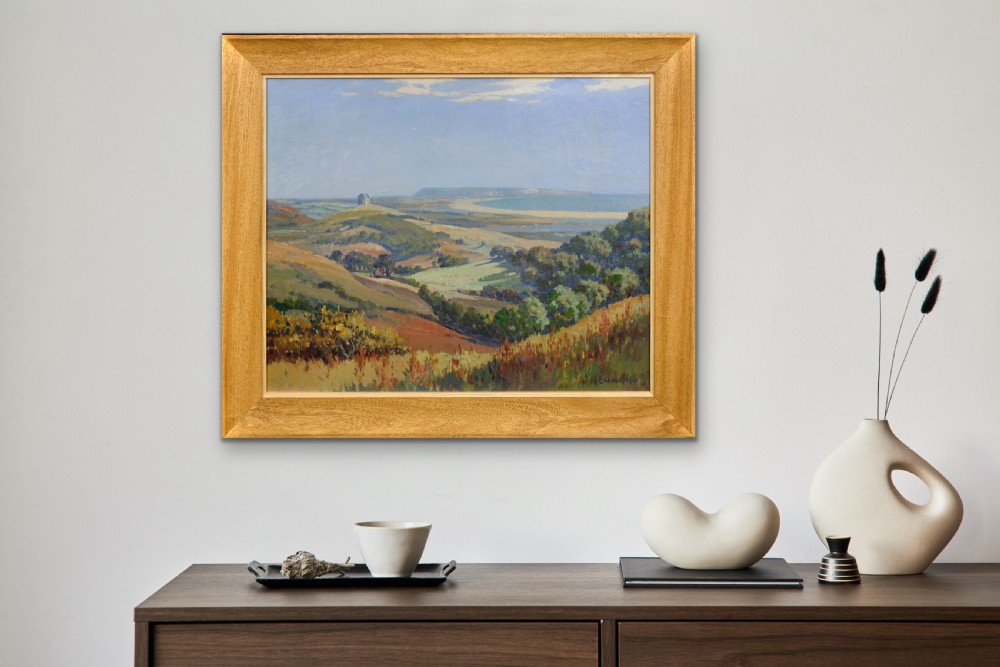 A framed oil painting depicting a rolling green and ochre coastal landscape overlooking Chesil Beach and Portland under a pale blue sky. View XII