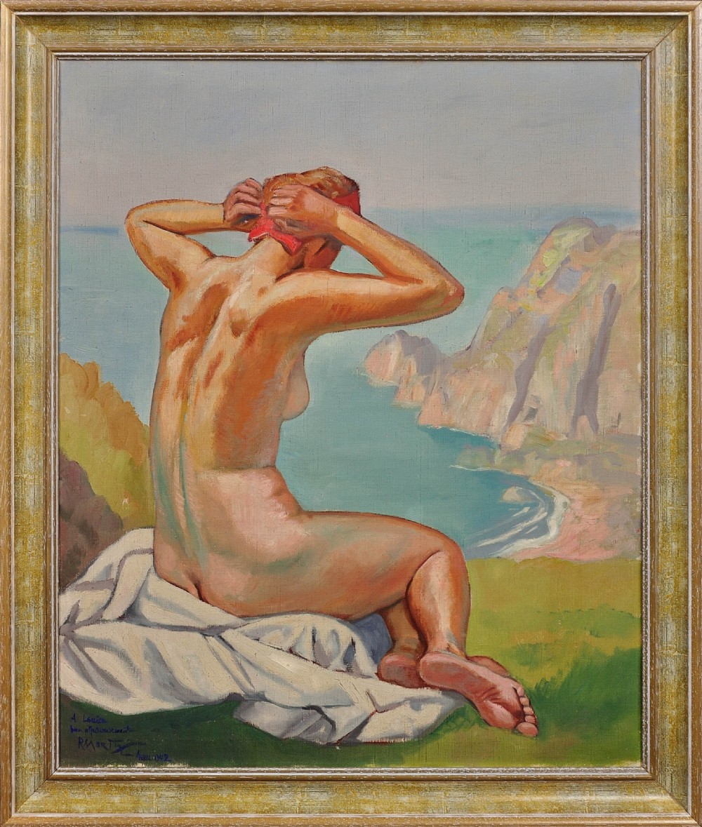 A framed 1920s oil painting depicting a nude female figure seated on a grassy cliff adjusting a red headscarf, with a coastal bay and sea cliffs in the background.