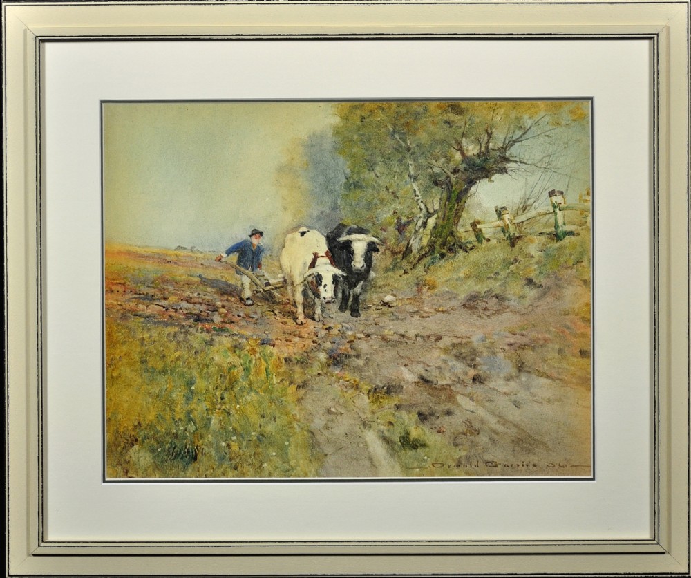 Framed Edwardian watercolour painting by Oswald Garside depicting two cattle pulling a plough through a field alongside a farm worker, presented in a light cream frame.