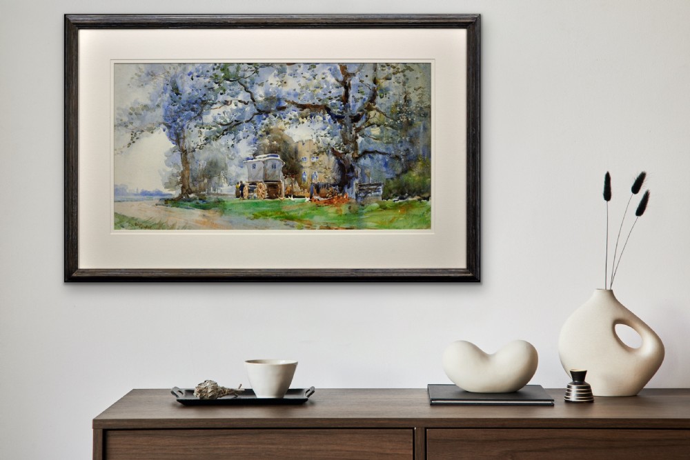 A framed watercolour painting depicting a traditional Romany gypsy caravan parked under large trees beside a stone building. View X