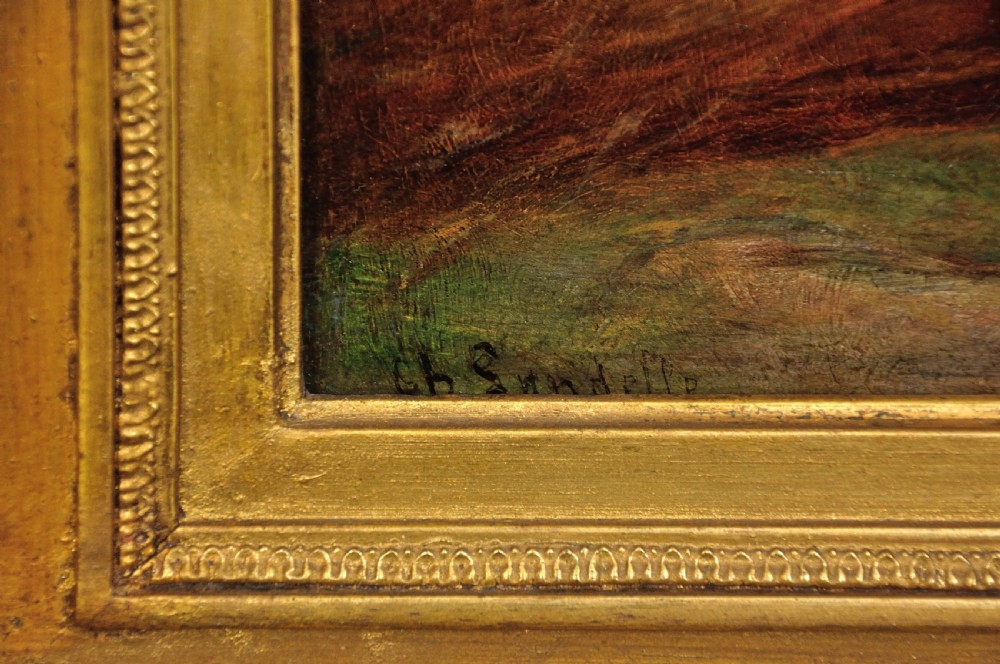 A framed 19th-century French oil painting depicting a couple seated in a harvest field, set within a wide gilded frame featuring leaf motifs. View III
