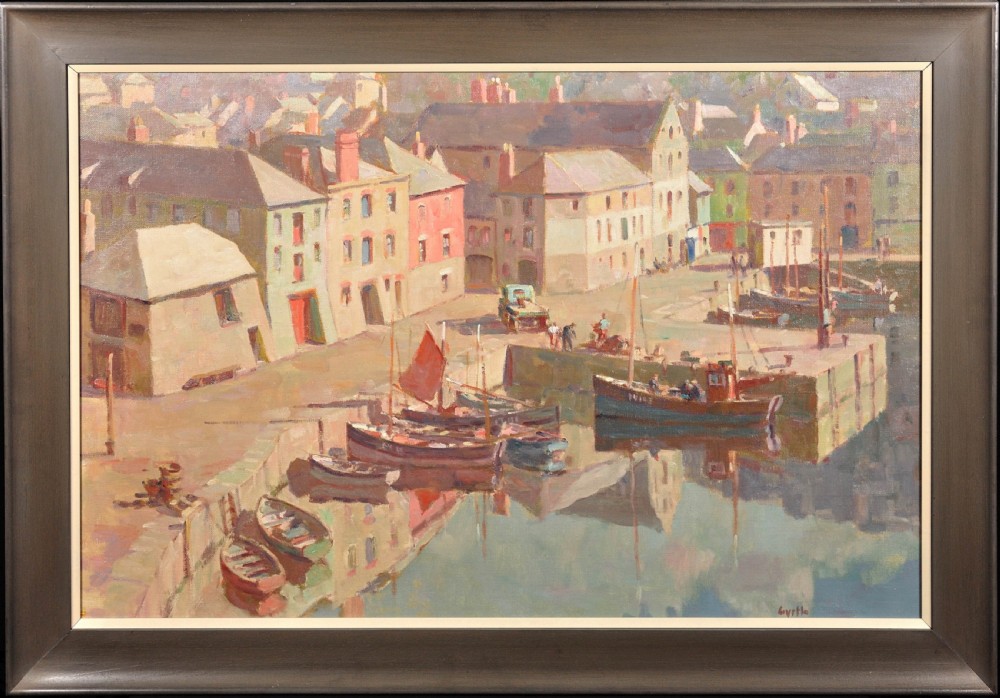 A framed mid-century oil painting depicting a calm Cornish harbour with pastel-painted buildings and moored fishing boats reflected in the water.