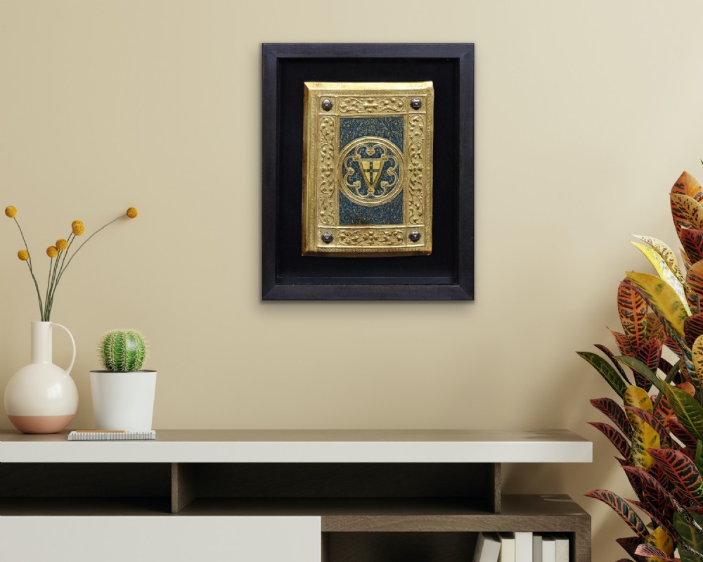 A framed rectangular gilded wooden book cover panel featuring punchwork, foliate borders, four metal corner studs, and a central coat of arms set against a blue painted background. View XXI