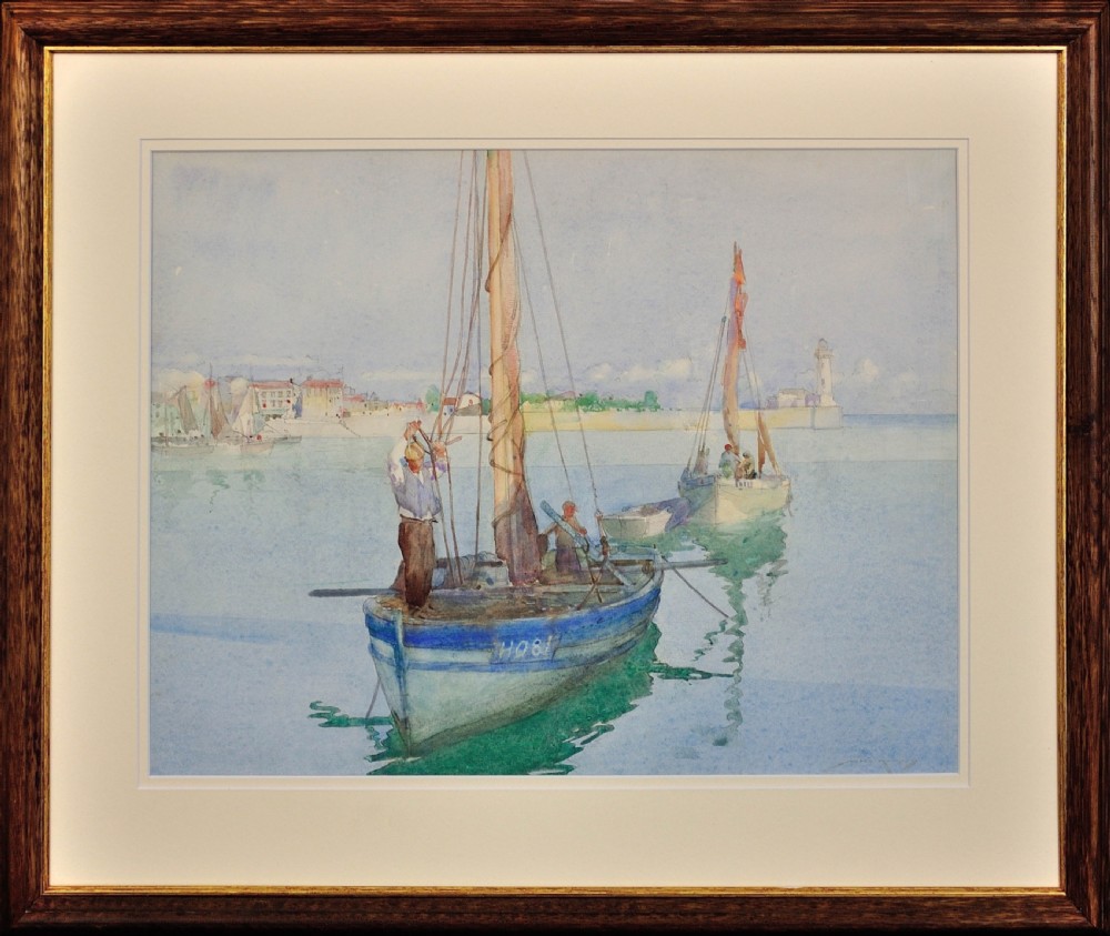 A framed watercolour painting depicting fishermen on blue wooden boats anchored in a still harbour with buildings and a lighthouse in the background.