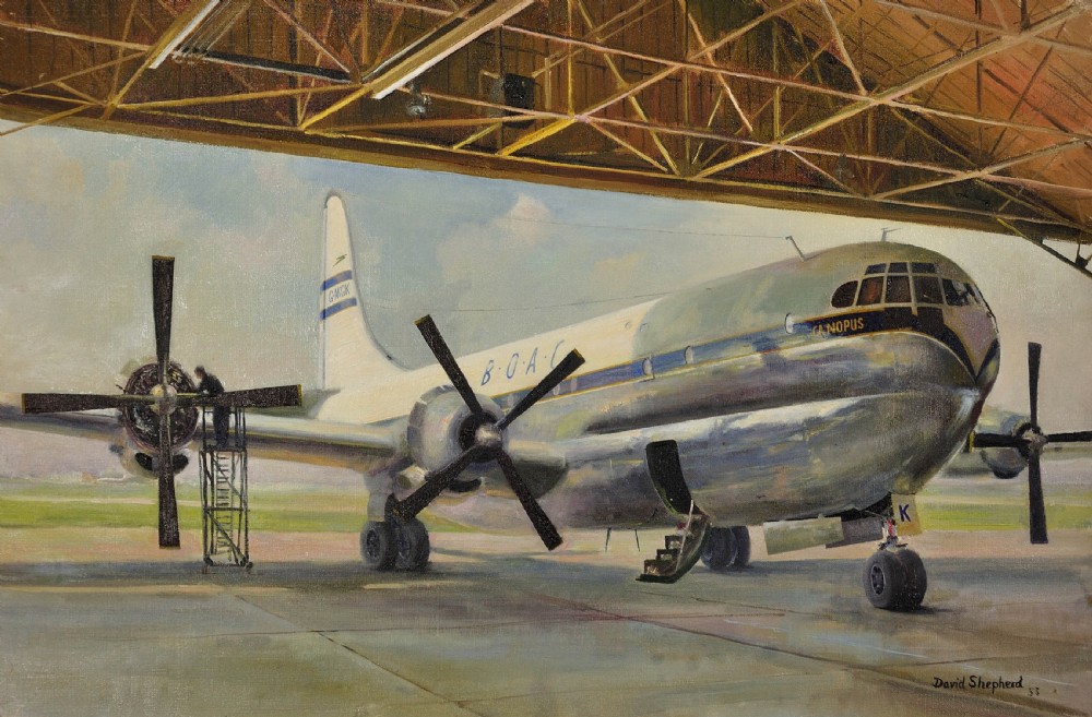 A framed oil painting depicting a BOAC Boeing Stratocruiser aircraft inside a large open hangar undergoing maintenance. View II