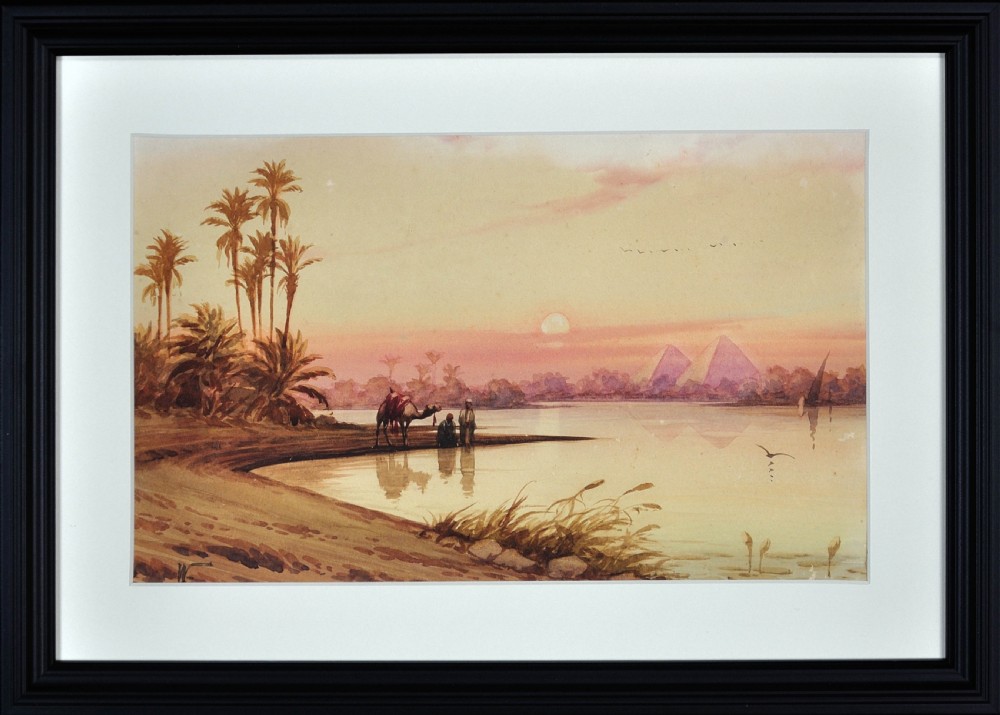 A framed watercolour painting depicting figures with a camel along the River Nile at sunset, with distant pyramids visible beneath a warm ochre sky.