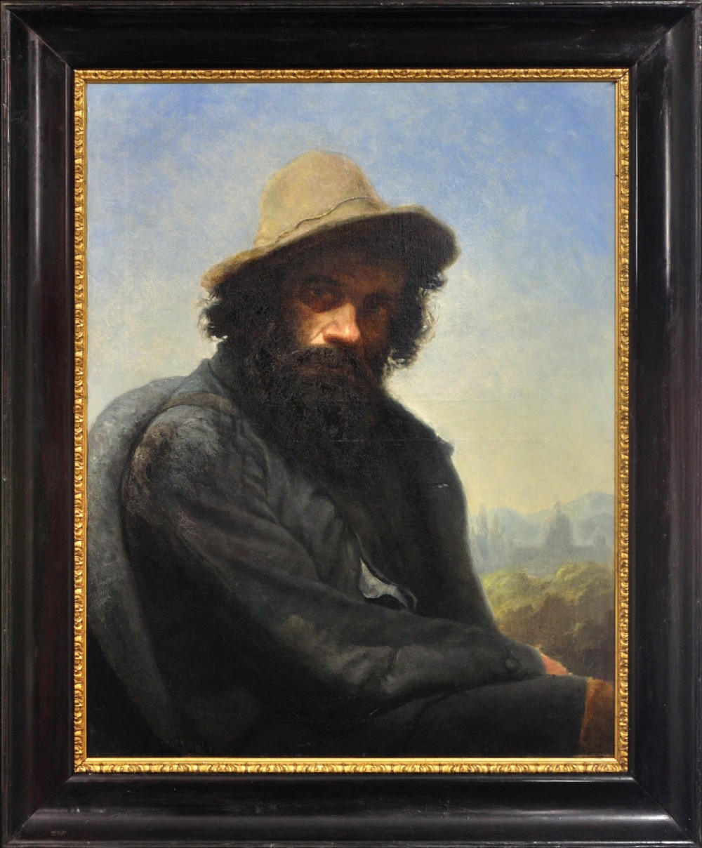 A 19th-century framed oil portrait depicting a bearded man wearing a hat and dark coat against a soft landscape background, housed in an ebonised frame with a gilt slip.