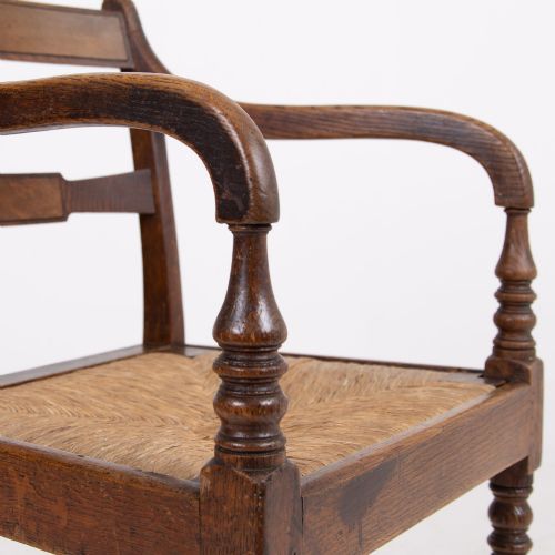 fig 1. A pair of 1820s Georgian dark oak elbow chairs featuring woven rush seats, swept armrests, and turned front legs.