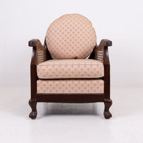 fig 3. A pair of 1920s dark wood bergere armchairs featuring circular woven cane backs, cane sides, and pink fan-pattern upholstered cushions.