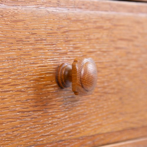 fig 3. A 1930s light oak sideboard featuring three upper drawers over three panelled cupboard doors with wooden knob handles.