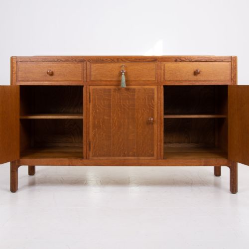 fig 4. A 1930s light oak sideboard featuring three upper drawers over three panelled cupboard doors with wooden knob handles.