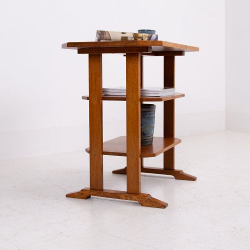 fig 1. An antique Cotswold School solid oak side table featuring three rectangular shelves supported by straight uprights and sled feet.