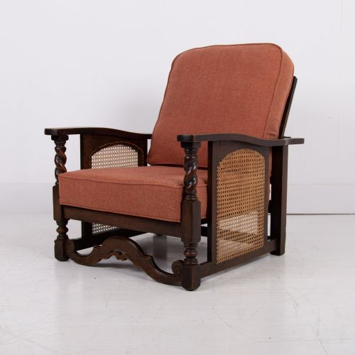 fig 1. A pair of dark oak Edwardian armchairs featuring barley twist front supports, woven cane side panels, and thick terracotta fabric cushions.