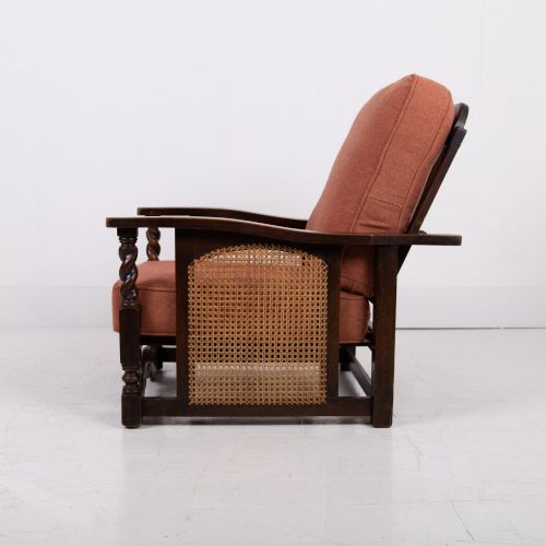 fig 2. A pair of dark oak Edwardian armchairs featuring barley twist front supports, woven cane side panels, and thick terracotta fabric cushions.