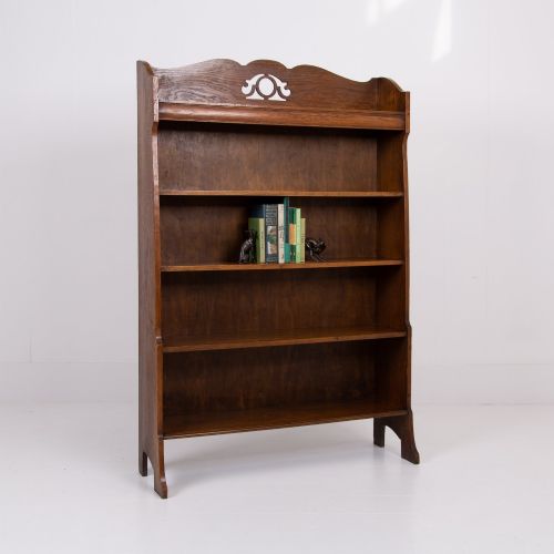 fig 1. An Arts and Crafts solid oak open bookcase featuring five shelves, shaped side panels, and a decorative cresting rail with a pierced central cutout.