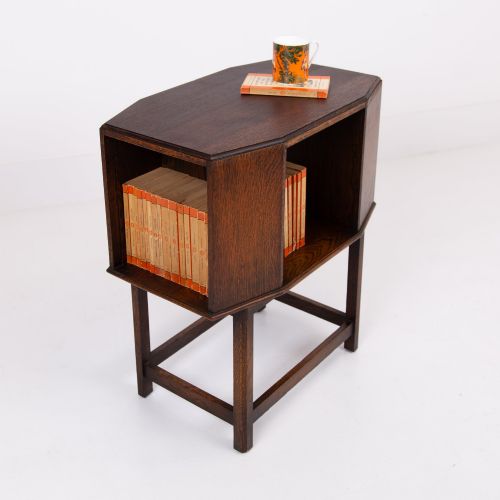 fig 1. An Art Deco dark oak side table featuring an octagonal top, open central niche, side book compartments, and straight legs with square stretchers.