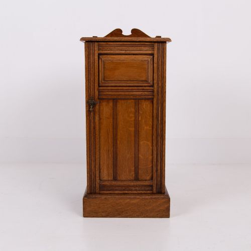 fig 1. A slim Victorian oak pot cupboard featuring a single panelled door with a small brass latch, resting on a solid plinth base with a gallery top.