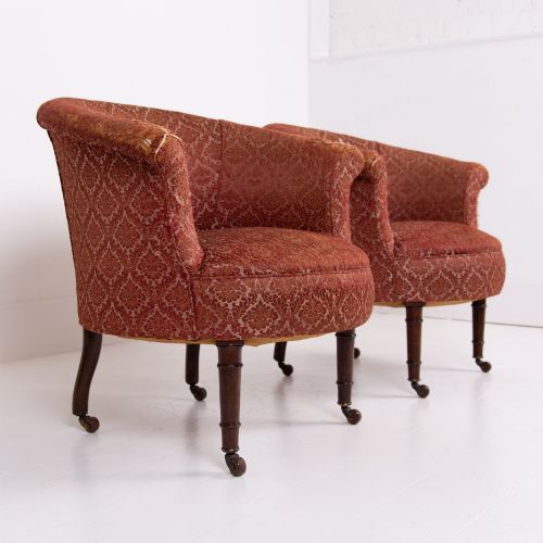 fig 1. A pair of 19th-century Victorian tub armchairs upholstered in patterned red fabric with turned wooden legs on brass castors.