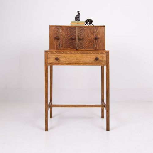 fig 1. A 1930s warm brown oak writing desk featuring a top compartment with cupboard doors, side fold-out sections, and a single drawer on square legs.