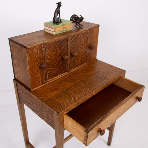 fig 2. A 1930s warm brown oak writing desk featuring a top compartment with cupboard doors, side fold-out sections, and a single drawer on square legs.