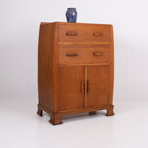 fig 1. A 1930s Art Deco medium brown oak tallboy cabinet featuring two upper drawers with carved wooden handles and a double-door cupboard below.