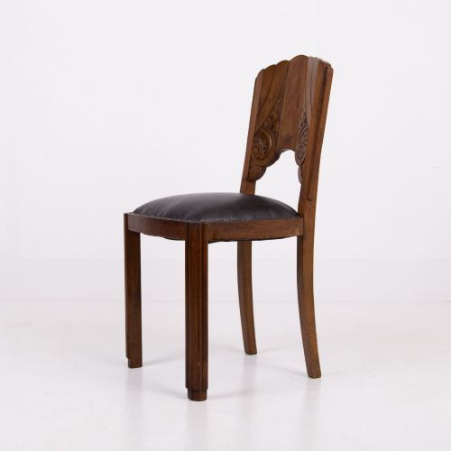 fig 2. A set of four dark walnut dining chairs featuring carved sunburst motifs on the backs and dark leather upholstered seats.