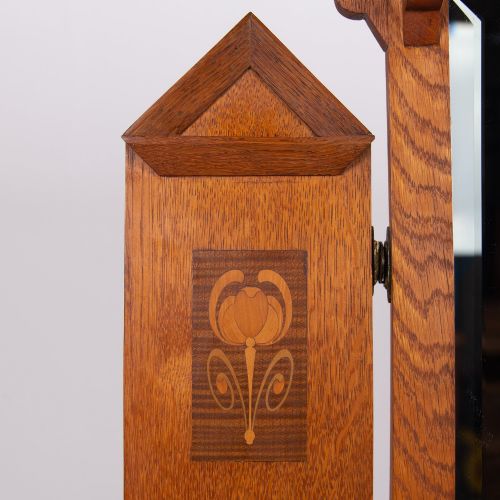 fig 2. An Arts and Crafts oak dressing chest featuring a superstructure with a central mirror, inlaid side panels, and small jewellery drawers above a chest of drawers.