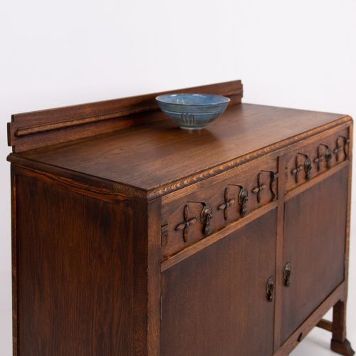 fig 1. A 1930s warm brown oak sideboard featuring two carved top drawers above a double-door cupboard, supported by block legs and a low stretcher base.