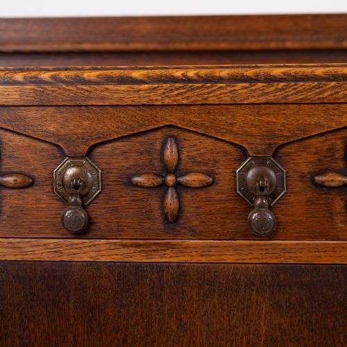 fig 2. A 1930s warm brown oak sideboard featuring two carved top drawers above a double-door cupboard, supported by block legs and a low stretcher base.